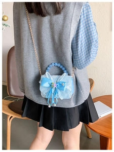 Detail of light blue lace girl's handbag with satin bow and pearl bead handle