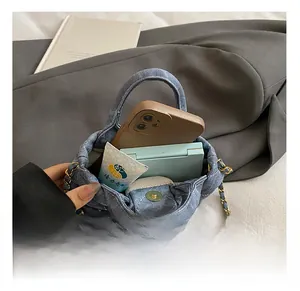 Detail showing internal capacity of blue quilted denim mini bag with chain strap