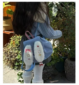 Detail of light blue corduroy backpack with plush bunny ears and decorative star charms
