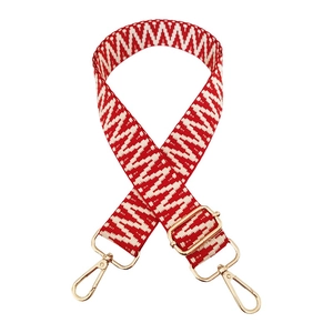 Close-up of red and white zig-zag woven bag strap with golden metal swivel hooks