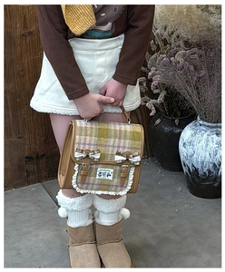 Detail of plaid kids backpack with lace trim and cute bows in warm autumn studio setting