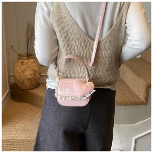 Détail du sac à bandoulière rose cœur avec dentelle et pendentif en peluche