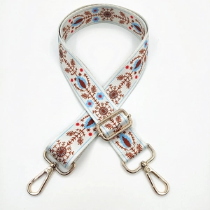 Detail of floral ethnic embroidery strap with golden metal lobster clasps and buckles
