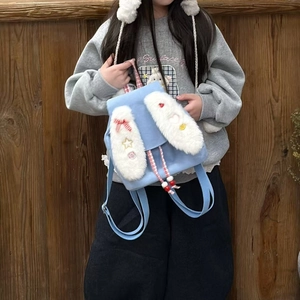 Detail of light blue plush bunny ear backpack with colorful star charms and bow for kids