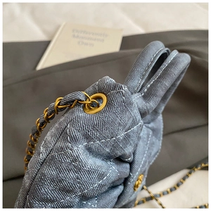 Detail of blue denim quilted bag with bow design and gold chain shoulder strap