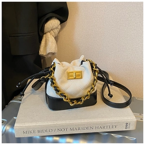 Close-up of mini bucket bag with quilted texture, gold chain and metal twist lock