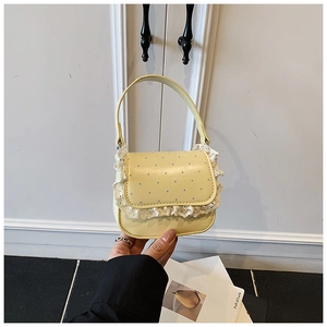Détail de bordure en dentelle et pois bleus sur un sac à main jaune en cuir synthétique