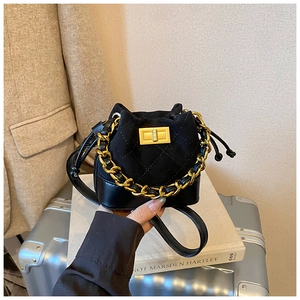Detail of black mini bucket bag featuring quilted stitching and golden chain handle