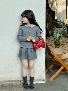 Close-up of gray knit cardigan with sequin collar and pleated skirt for kids