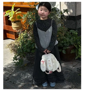 Girl wearing a plush bunny ear backpack with floral outfit in a sunny outdoor garden