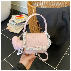 Détail d'un sac rose à pois avec dentelle blanche et pendentif cœur en peluche
