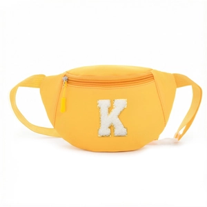 Detailed view of yellow waist bag featuring plush white letter K with gold sequins
