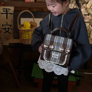 Retro plaid kids backpack with bow and lace detail shown on a model in a warm setting