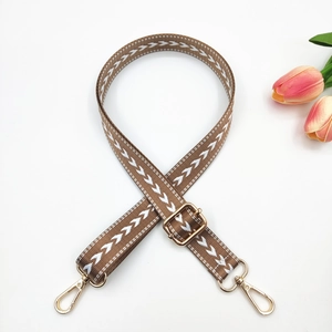 Détail de la bandoulière réglable en nylon avec motif flèche marron et boucles dorées