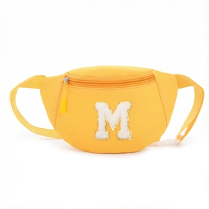 Detail of yellow nylon waist bag for kids featuring a plush white letter M patch