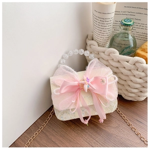 Detail of cream lace mini bag with pink silk bow, pearls and chain for kids