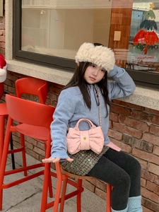 Pink quilted bow handbag for kids with gold chain strap in an outdoor setting