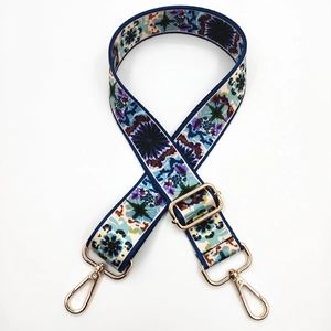 Close-up of adjustable floral strap with golden metal buckles for crossbody bags