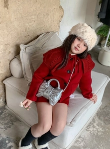 Detail of silver quilted bow chain bag paired with a festive red knit cape and headband