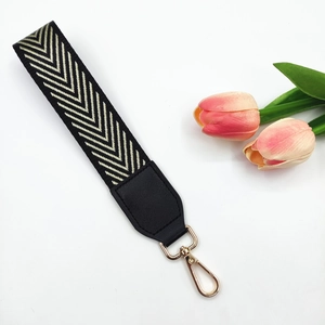 Detail of black and gold woven wristlet strap with chevron pattern and metal lobster clasp