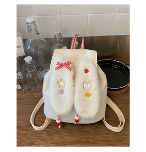 Detail of plush rabbit ears and red checkered bow on a white corduroy kids backpack