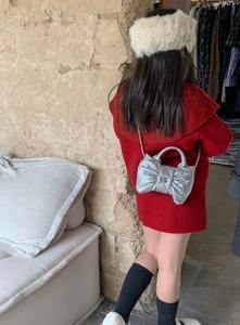 Silver quilted kids bag with metallic bow and chain strap shown on a red dress model