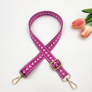 Détail de la bandoulière en nylon violet avec motifs en V blancs et boucles dorées