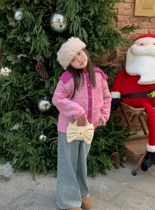 Pink knit cardigan and white bow handbag styled in a cozy Christmas setting