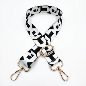 Detail of adjustable black and white geometric bag strap with gold metal lobster hooks