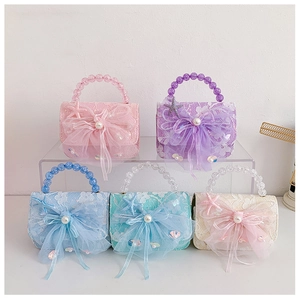 Detail view of colorful lace mini handbags with ribbon bows and pearl beaded handles