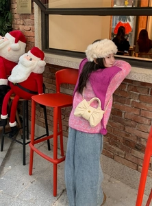 Close-up of kids' pink quilted bow handbag with chain strap and winter outfit detail