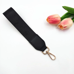 Macro shot of black nylon strap with golden lobster clasp and faux leather reinforcement