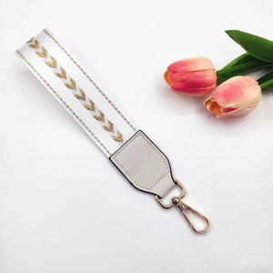 Close-up of heart embroidered strap with golden metal lobster clasp and leather joints