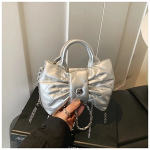 Detail of silver quilted bow shoulder bag with metal texture and floral clasp detail