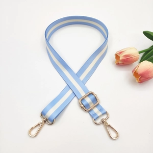 Detail of adjustable blue and white striped bag strap with shiny gold metal hooks