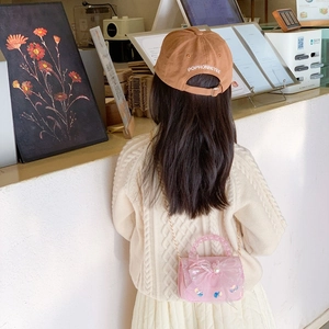 Pink mini handbag for girls featuring large mesh bow and pearl handle in casual cafe setting