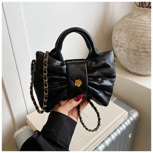 Detailed close-up of a quilted black bow shoulder bag with a gold camellia flower clasp