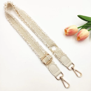 Elegant off-white woven shoulder strap with fringe edges and gold metal hardware