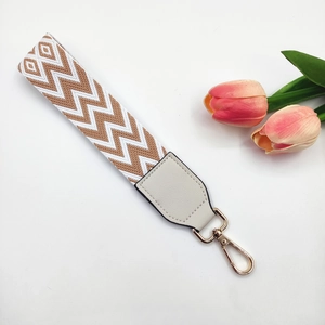 Detail of woven wrist strap with brown and white chevron pattern and gold metal clasp