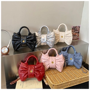 Detail view of quilted bow-shaped crossbody bags in six vibrant colors with chain straps