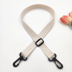 Close-up of beige woven shoulder strap with black plastic swivel hooks and adjuster