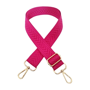 Close-up of rose red woven shoulder strap with arrow pattern and gold metal buckles