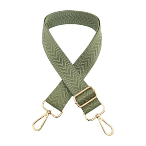 Close-up of sage green adjustable bag strap with chevron embroidery and gold metal clips