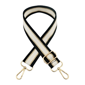 Detail of adjustable black, white, and gold striped wide fabric bag strap with gold hooks