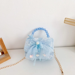 Close-up of light blue lace girl's handbag with sea star charm and pearl bow detail