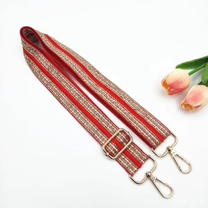 Detail of ethnic style red and gold embroidered bag strap with golden metal buckles