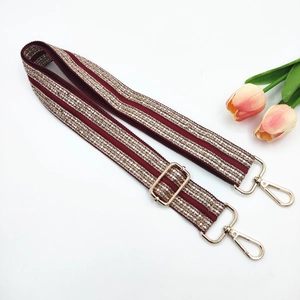 Macro view of burgundy ethnic embroidery strap with golden hardware and lobster clasps