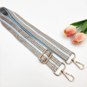 Detail of light blue embroidered bag strap with silver rhinestones and gold hardware
