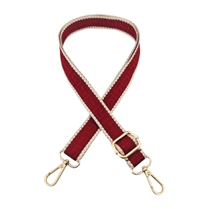 Detail of adjustable woven bag strap with red geometric pattern and gold lobster clasps