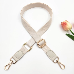 Detail of adjustable beige cotton strap with light gold hardware and grey leather parts